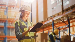 A woman in a hard hat and yellow safety vest - Order Management System Vendors