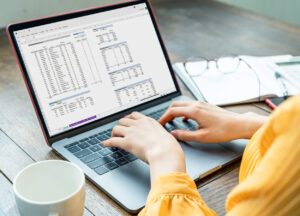 A person in a yellow shirt works on a laptop - Wholesale Order Management System