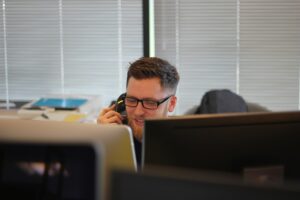 Smiling man with glasses talks on the phone - Order Management System Vendors 