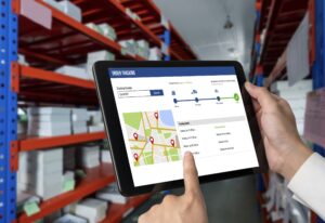 A worker uses a tablet showing a Wholesale Order Management System - Wholesale Order Management System