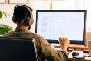 A man with headphones sits at a desk - Multi Channel Order Management