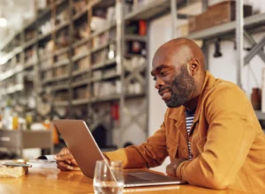 A man researches top Order Management System vendors on his laptop - Order Management System Vendors 