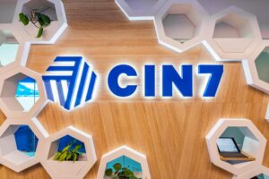 A wooden wall displays the blue and white CIN7 logo - Cin7 Alternatives