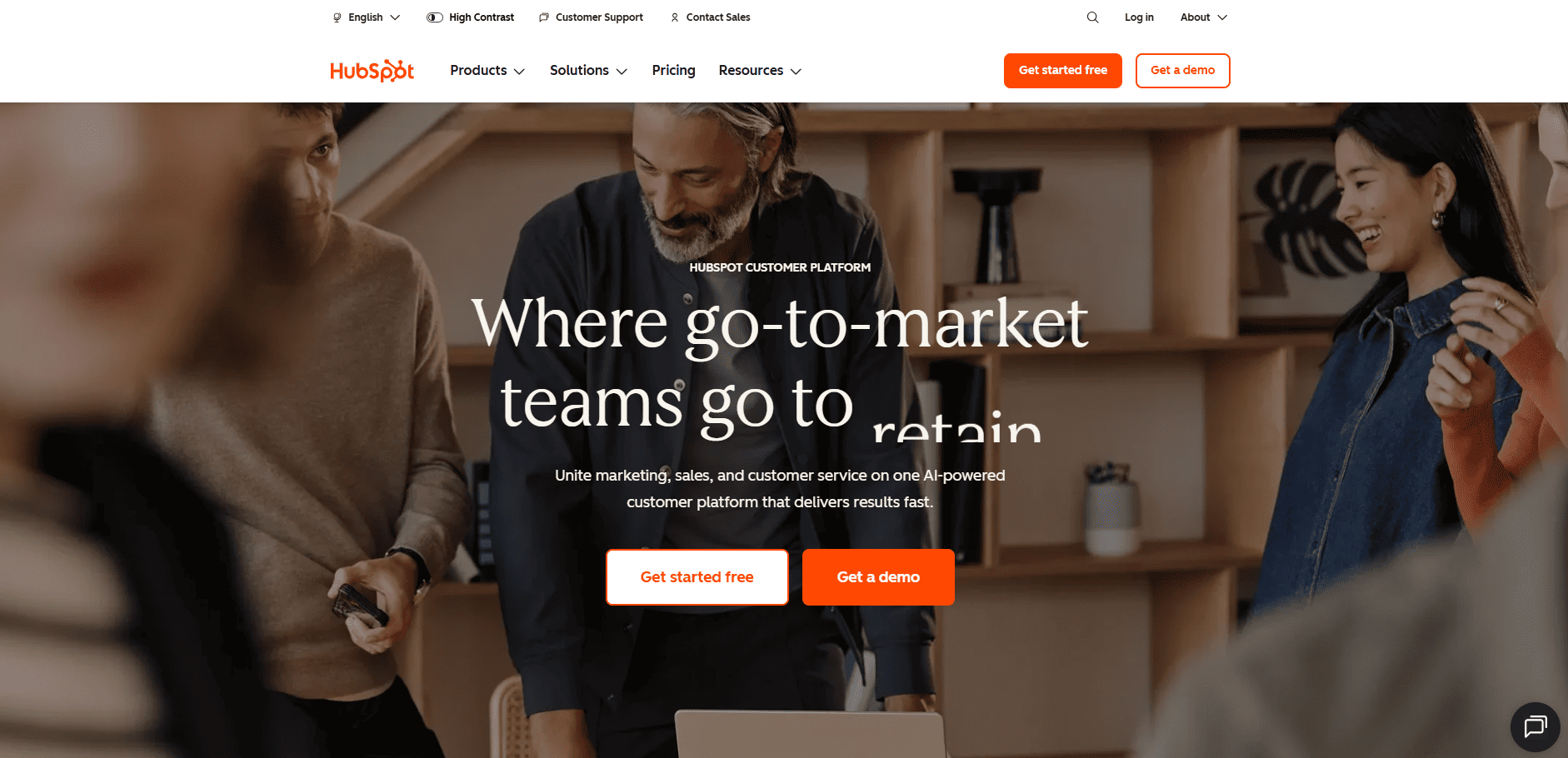 Smiling colleagues collaborate in a modern office with the HubSpot site overlay displaying retention messaging and action buttons.